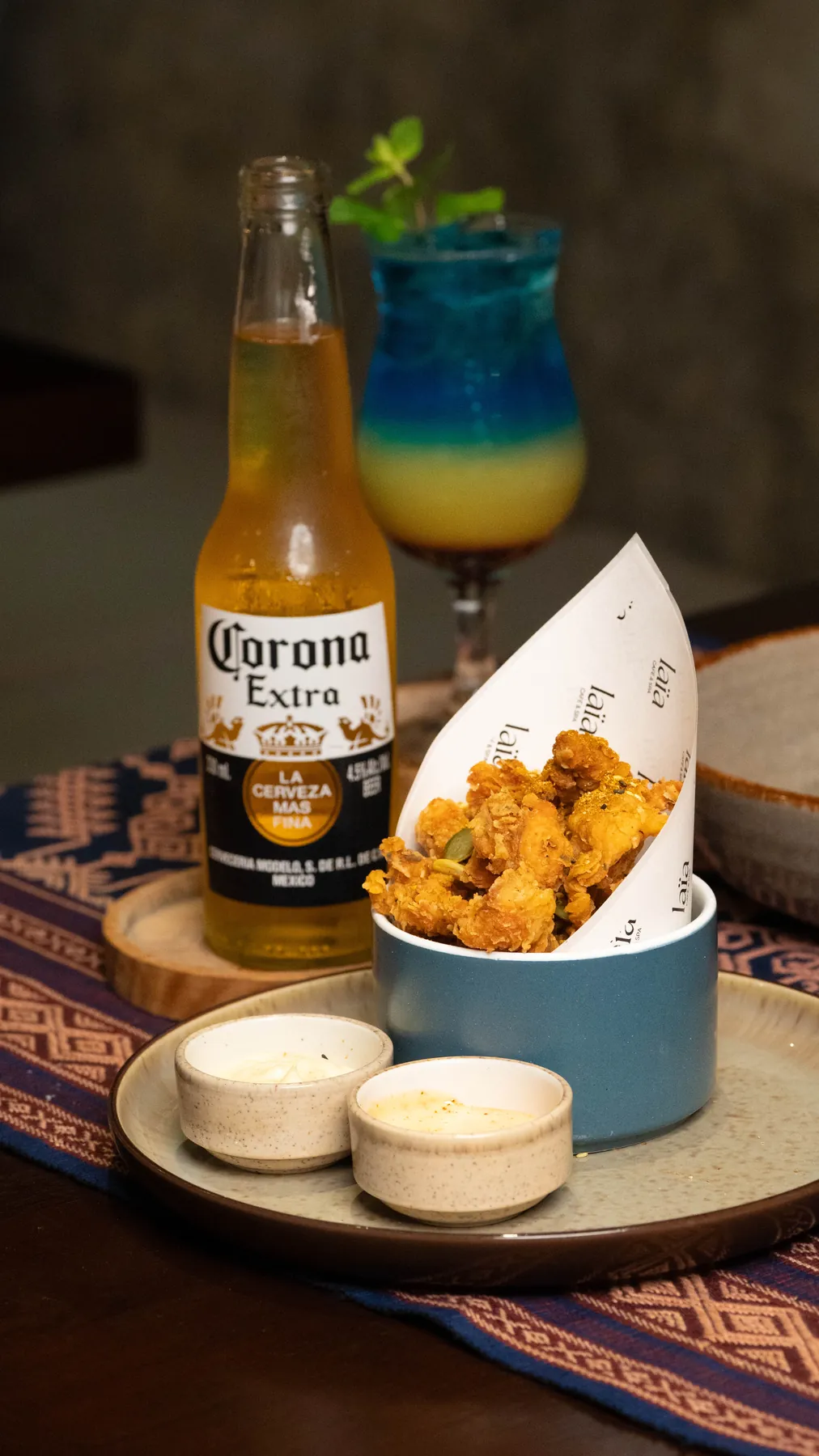 Popcorn chicken in a laïa cone with a Corona and a blue lagoon cocktail