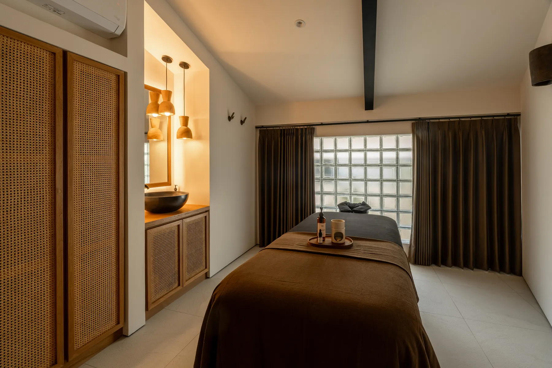 Spa room with rattan cabinet, basin, and warm pendant lighting