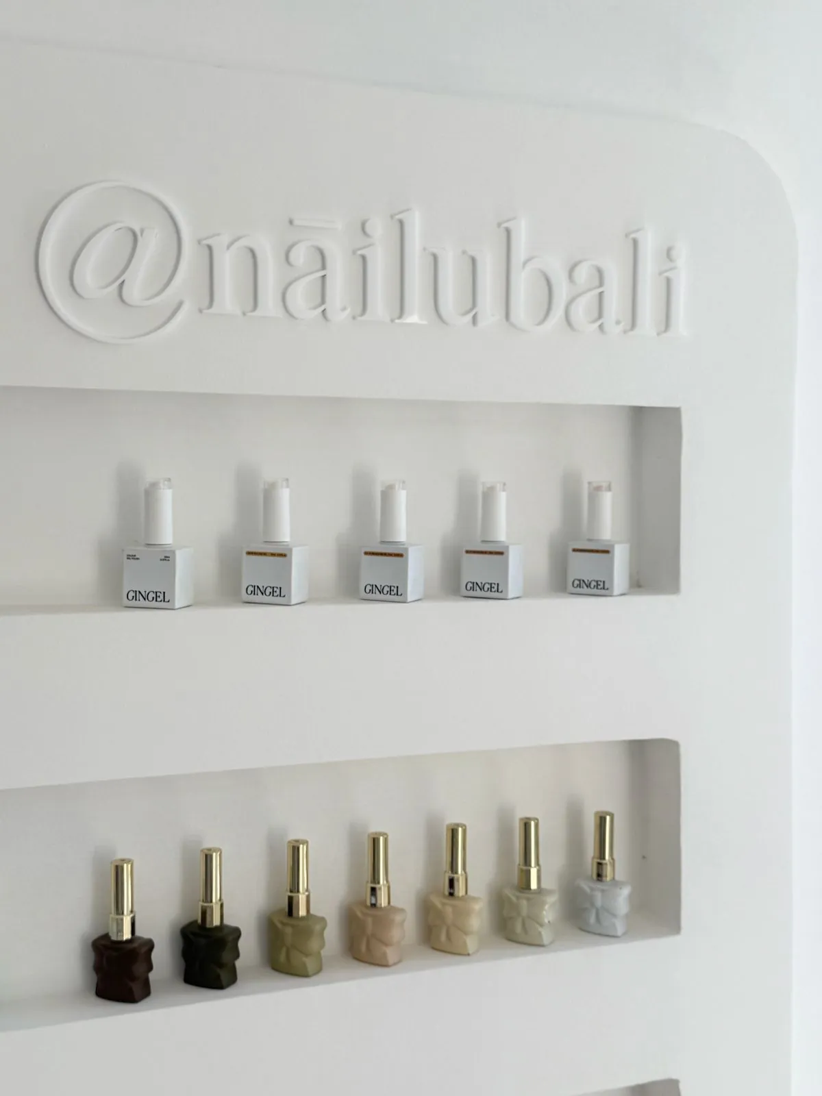 Nāilu gel polish shelves beneath the embossed @nailubali wall sign