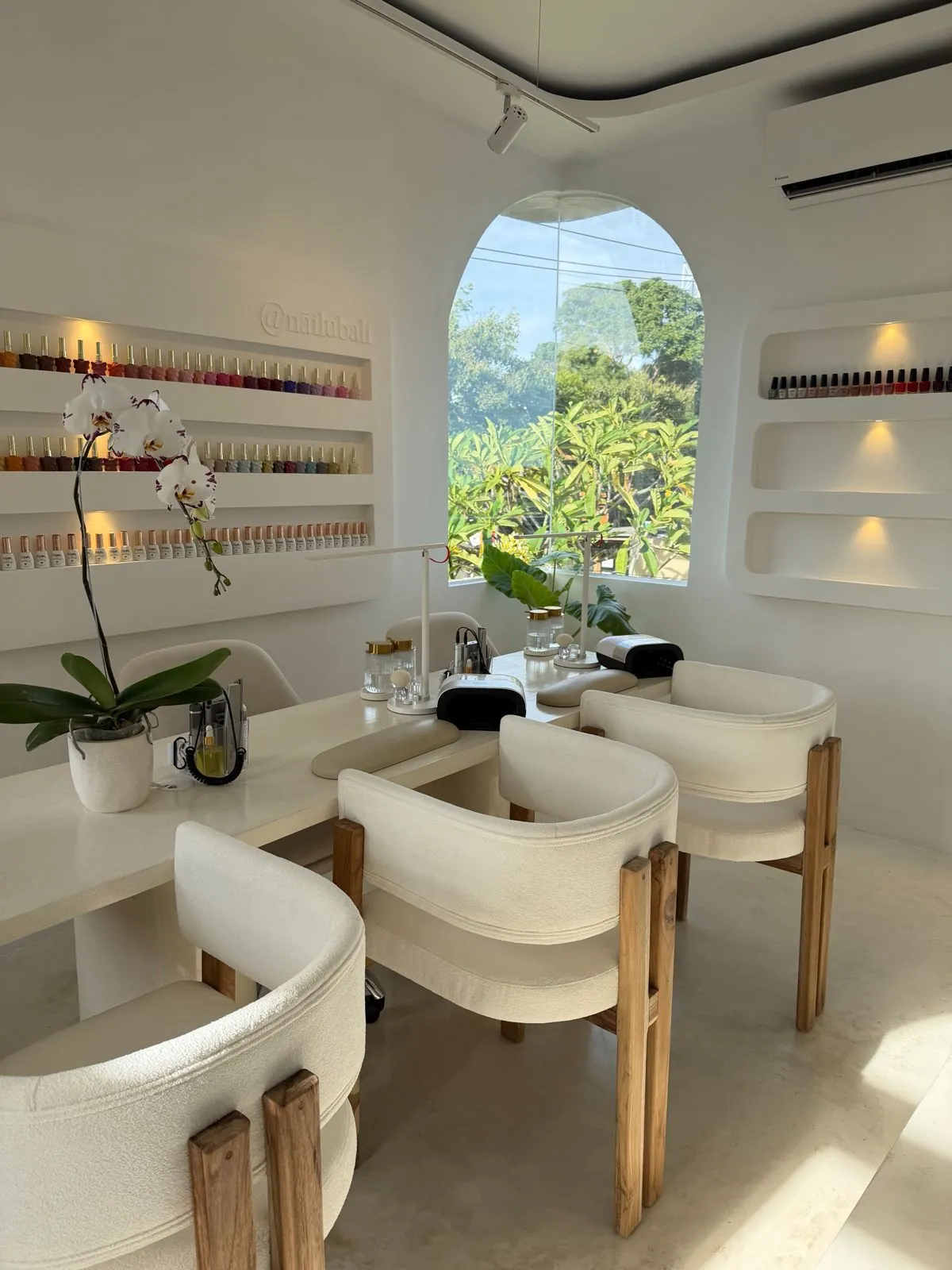 Nāilu nail studio with polish wall, arched window, and orchid