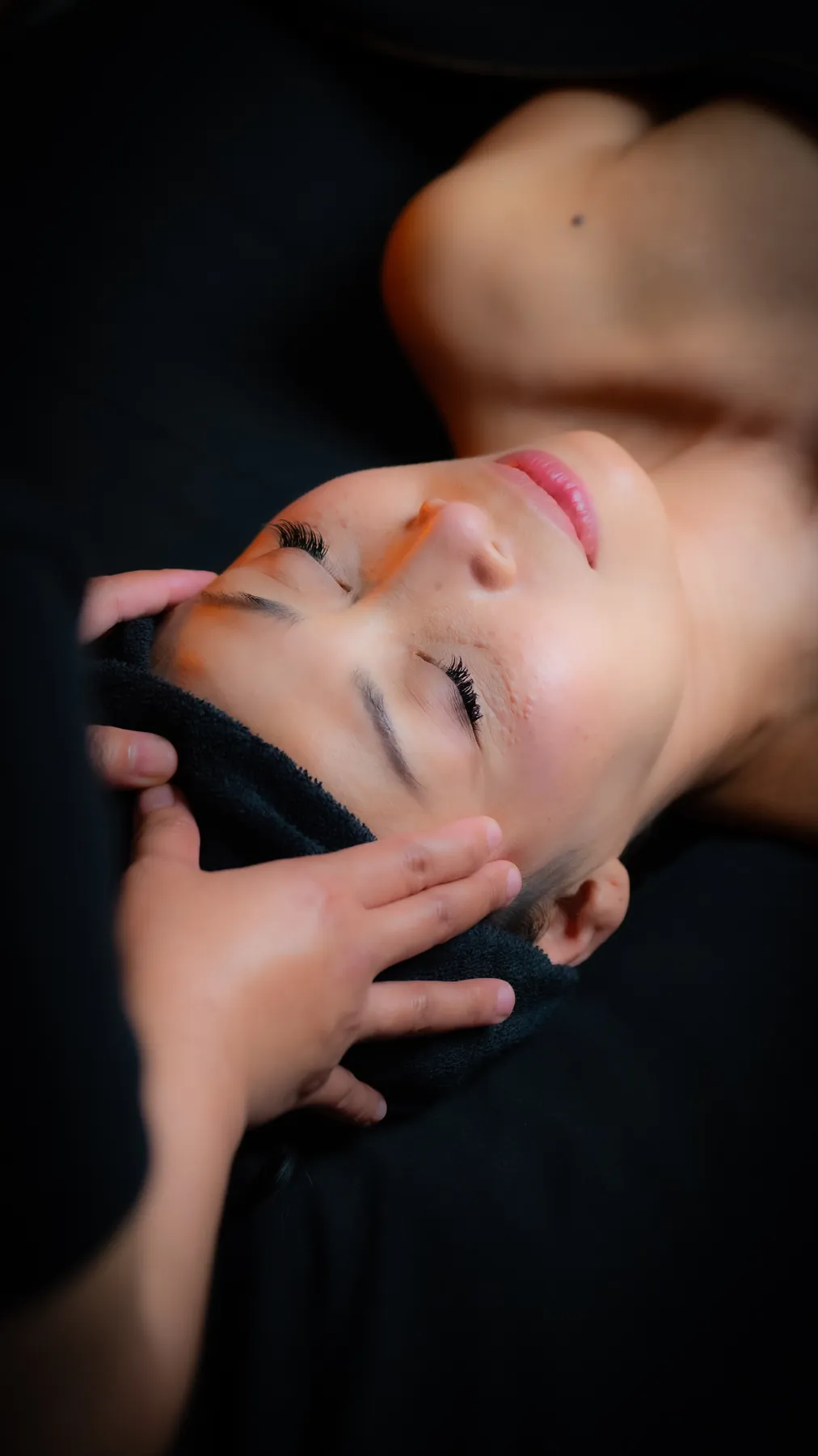 Facial massage with a guest resting under a warm towel