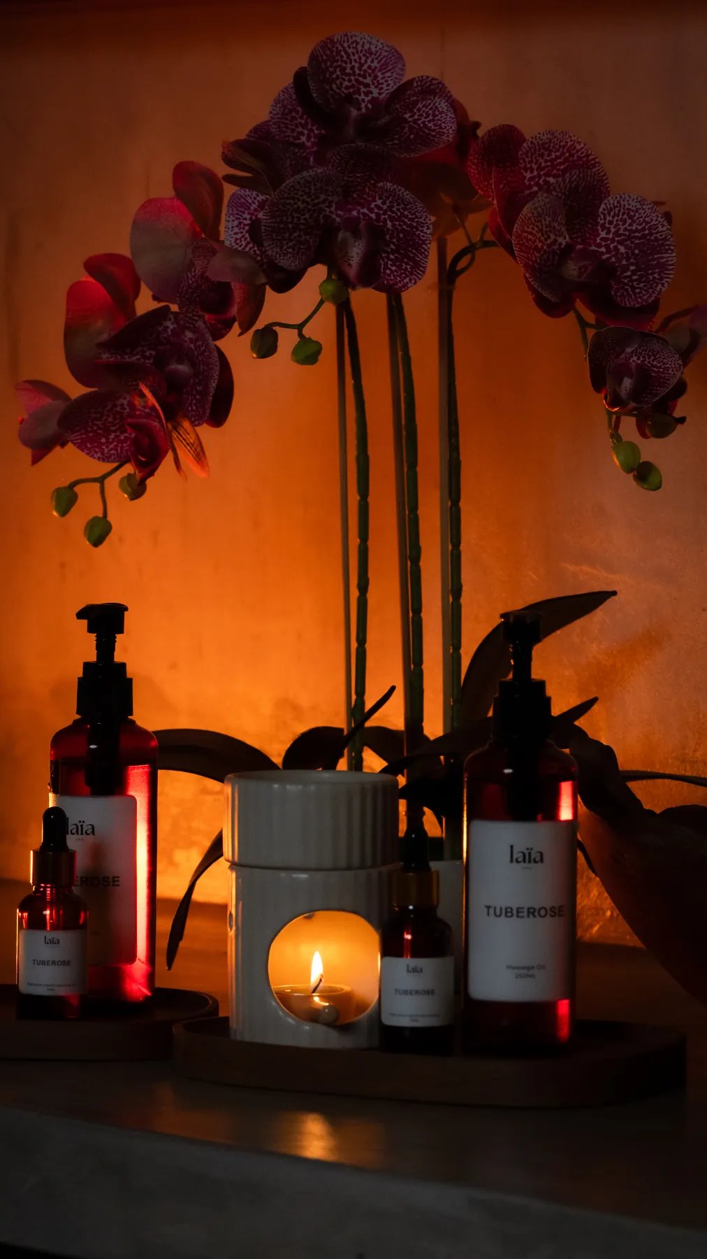 laïa tuberose massage oils beside an orchid and a lit burner